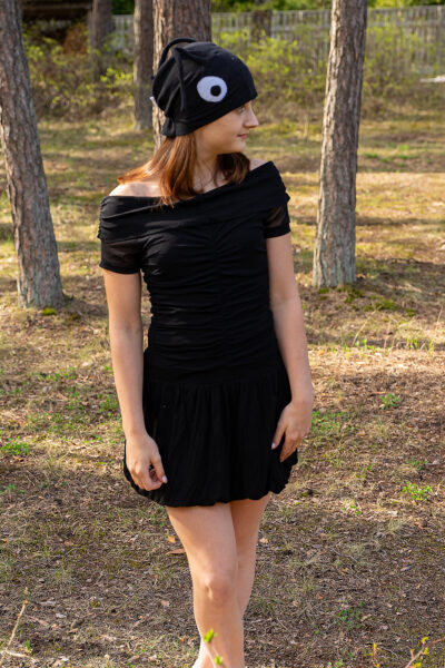 Noor naine seisab metsas, seljas must sipelgakostüüm: kroogetega kleit ja suure silmaga müts.