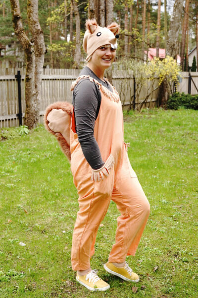 Rõõmsa näoga naine seisab õues ja kannab orava kostüümi, millel on saba, tunked ja peakate. Taustal on aed.