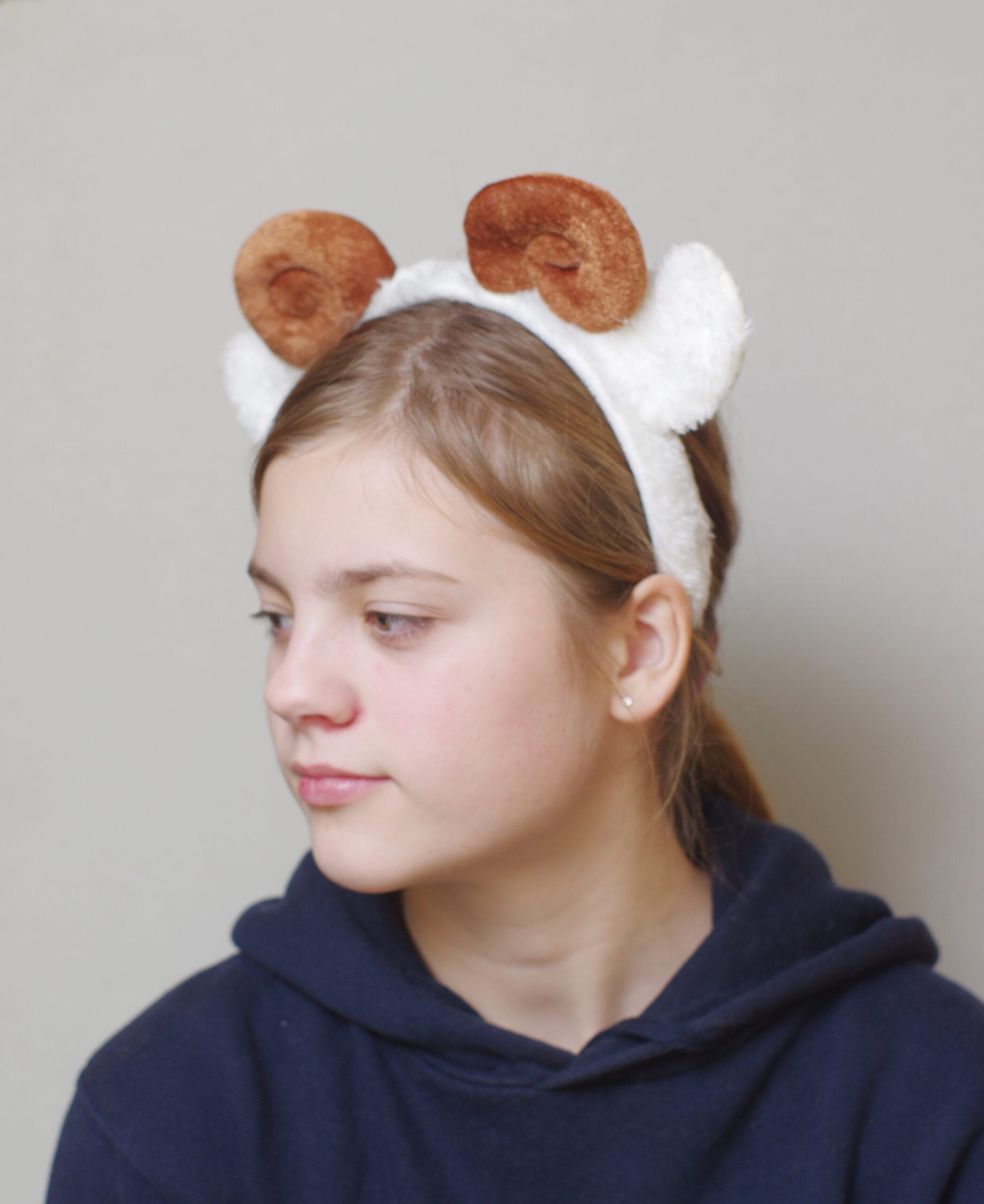 lapsel on peas pruunide keerdus sarvede ja valgete kõrvadega oina peavõru.