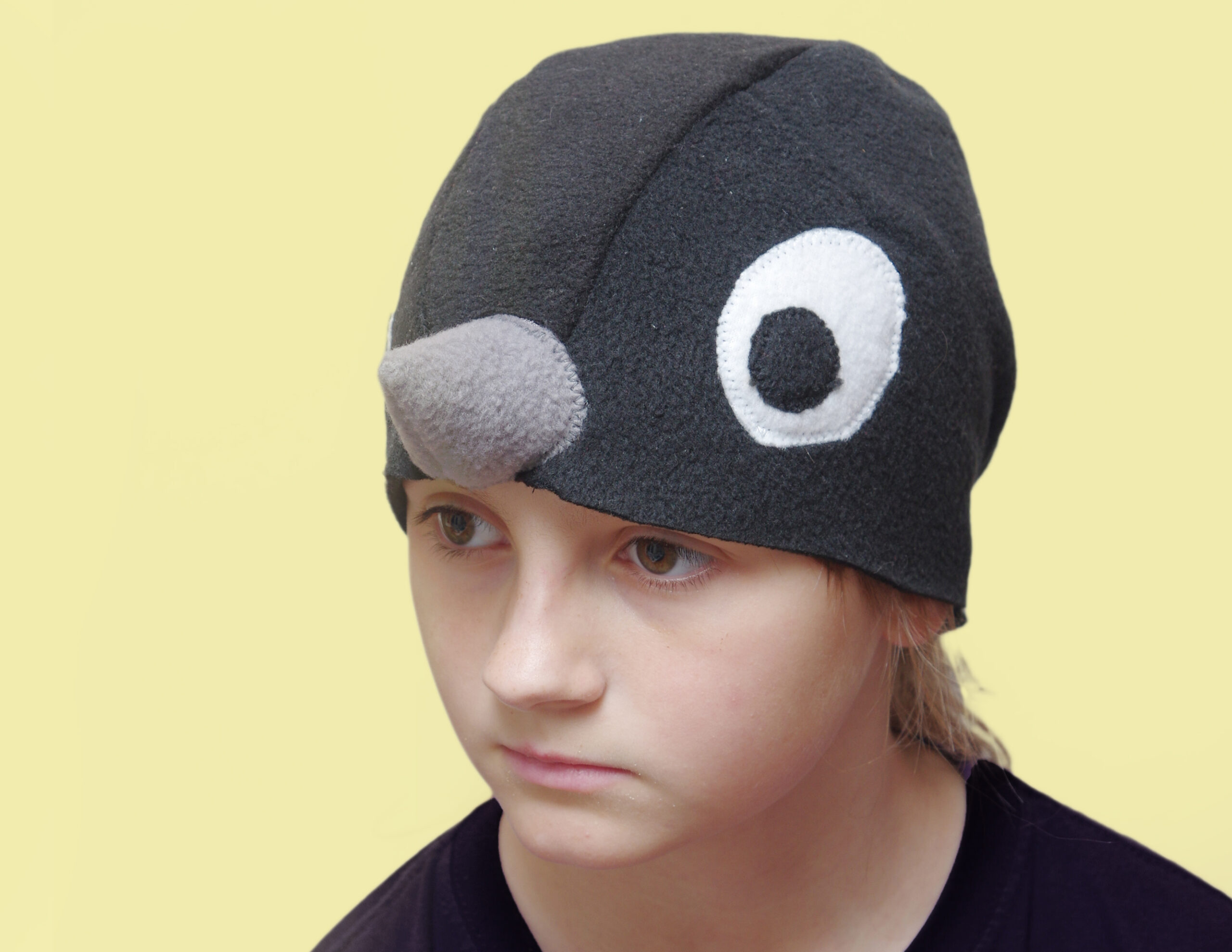 Halli nokaga musta linnu kostüümimüts lapse peas.