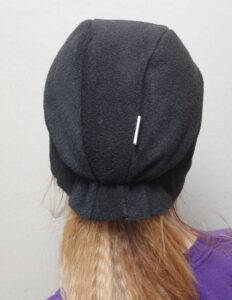 Suurte valgete silmadega ja halli nokaga musta linnu kostüümimüts lapse peas.