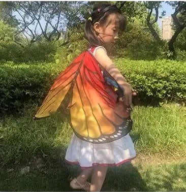 laps, kellel on oranžid õhukesest materjalist liblika tiivad