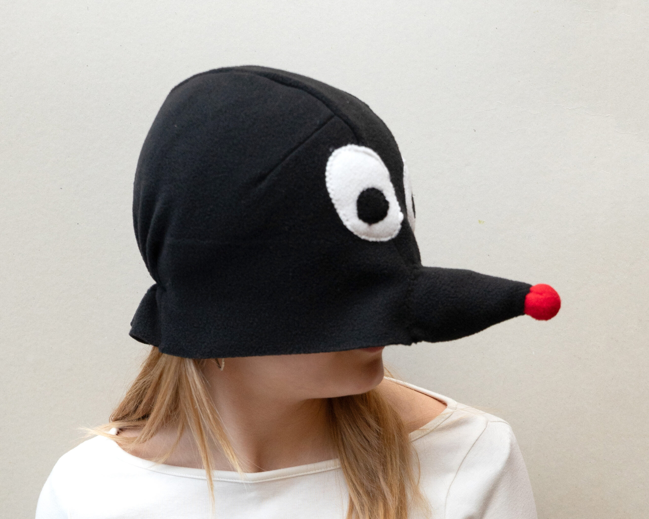 Punase nina ja suurte valgete silmadega fliisist muti kostüümimüts täiskasvanutele. Inimese nägu ei ole näha.