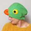 Handmade vibrant green fleece bird hat for adults with an orange beak and large yellow-black eyes.