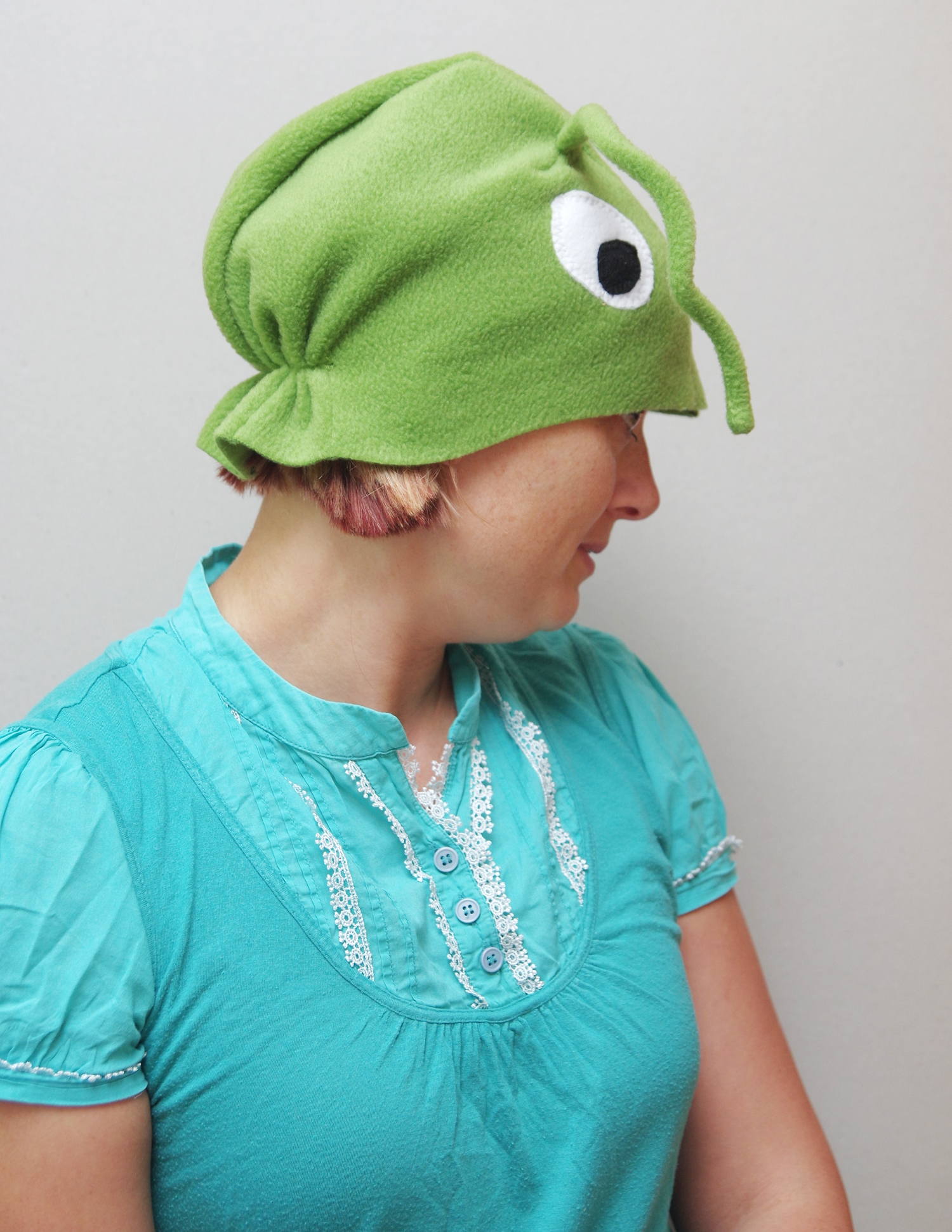 Naine kannab suurte valgete silmade ja pikkade tundlatega helerohelise rohutirtsu kostüümi.