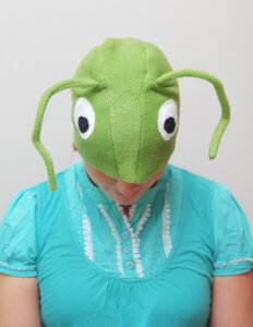 Naine kannab suurte valgete silmade ja pikkade tundlatega helerohelise rohutirtsu kostüümi.