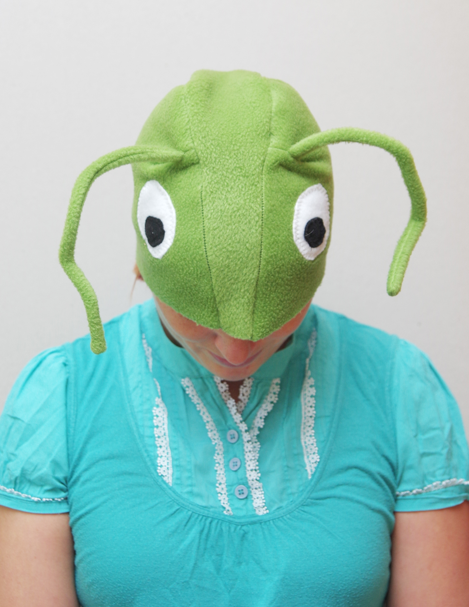 Naine kannab suurte valgete silmade ja pikkade tundlatega helerohelise rohutirtsu kostüümi.